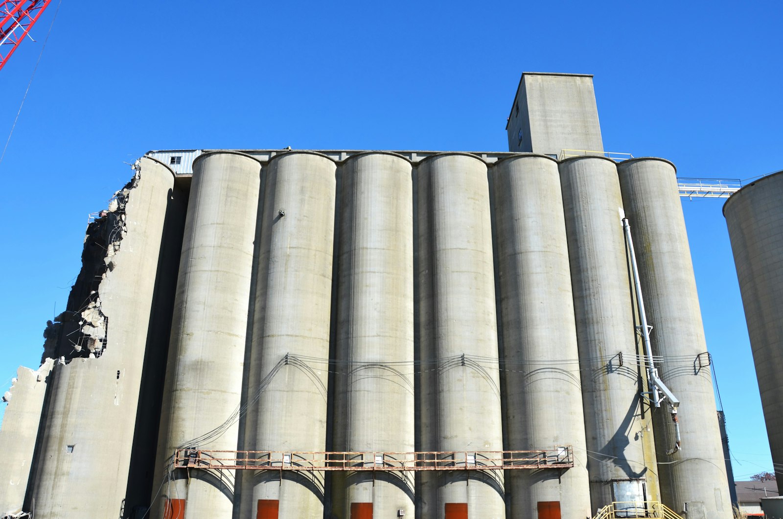 Betongsilos med synliga konstruktionsskador under blå himmel